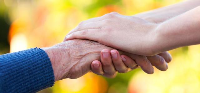 Close-up image of an elderly hand being held by a younger-looking hand